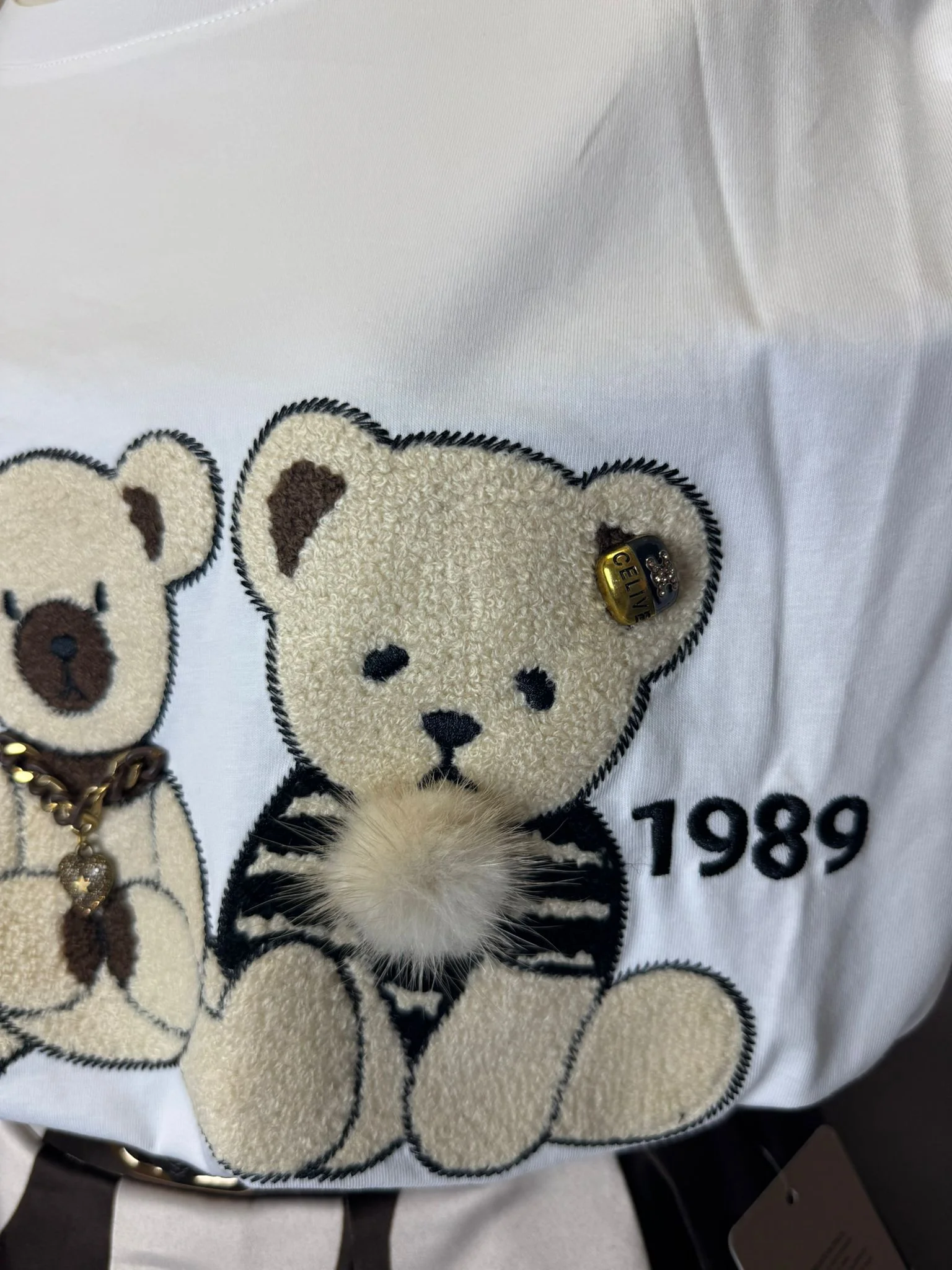 Tricou deosebit cu aplicații teddy 3D și detalii decorative, perfect pentru un look feminin și rafinat.